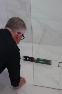 Registered building inspector in Melbourne using leveling tool to check tiled flooring alignment