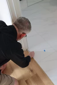 Home inspector checking flooring transition between timber and tile during a final house inspection.