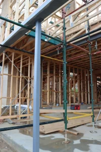 Lock-up stage inspection of a residential build, focusing on structural framing, scaffolding, and exterior installation progress.
