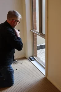 Home inspector examining window frame and seals during a new home final inspection.