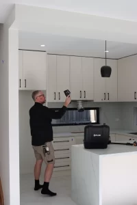 Building inspector using thermal imaging camera to check ceiling insulation and hidden defects in Melbourne home