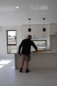 Inspector measuring kitchen bench level during Melbourne pre-handover inspection