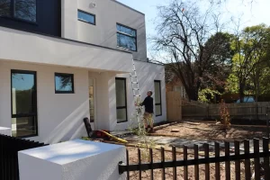 Inspector using ladder to check exterior eaves and roof area during Melbourne pre-handover inspection