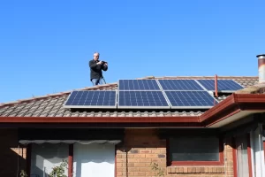 Technician inspecting solar panels on residential roof in Melbourne during autumn pre-winter maintenance check